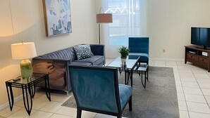 A modern living room with a sofa, armchair, coffee table, and TV stand. - Huge Lot, Private Pool Home Centrally Located (Kissimmee)