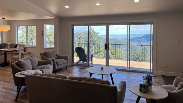 A spacious living room with a large sliding glass door leading to a balcony with a mountain view. - Beautiful, newly renovated mountain home. (Golden)