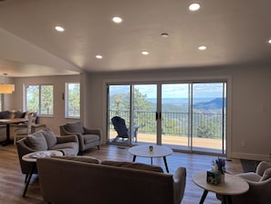 A spacious living room with a large sliding glass door leading to a balcony with a mountain view. - Beautiful, newly renovated mountain home. (Golden)