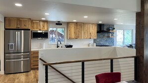 A modern kitchen with wooden cabinets, stainless steel appliances, and a stone backsplash. - Beautiful, newly renovated mountain home. (Golden)