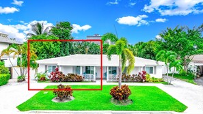 A white two-story house with a balcony, surrounded by lush greenery and palm trees. - Heated Pool! Close To Beach+Restaurants & Shops! (Fort Lauderdale)