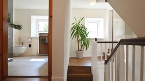 Una cocina moderna con un ventanal grande, una planta en maceta y una escalera de madera que sube a otro nivel.