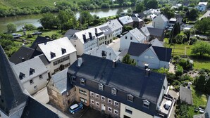 Un barrio residencial con casas, un río y colinas al fondo.