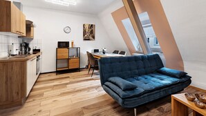 Una cocina moderna con armarios de madera, un rincón de comedor con un sofá azul, y vistas de la ciudad a través de una ventana.