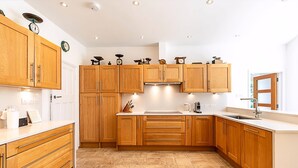 Eine Küche mit Holzausstattung, einer weißen Arbeitsplatte, einem Spülbecken und einer Uhr an der Wand.