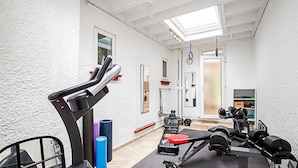 Ein Fitnessstudio mit Trainingsgeräten, Laufband und Spiegel.