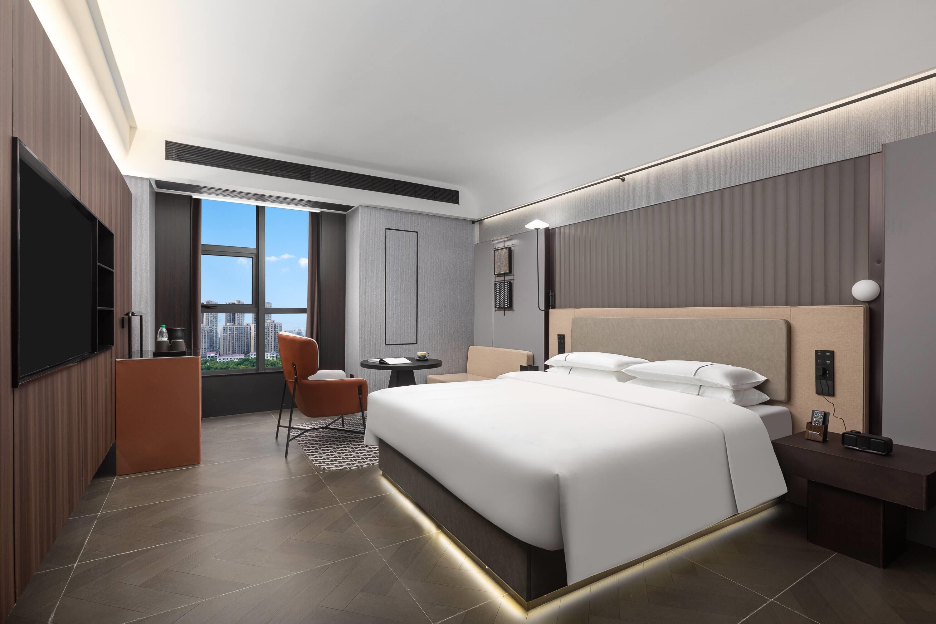 Une chambre d’hôtel moderne équipée d’un grand lit, d’un bureau, d’une chaise et d’un téléviseur.