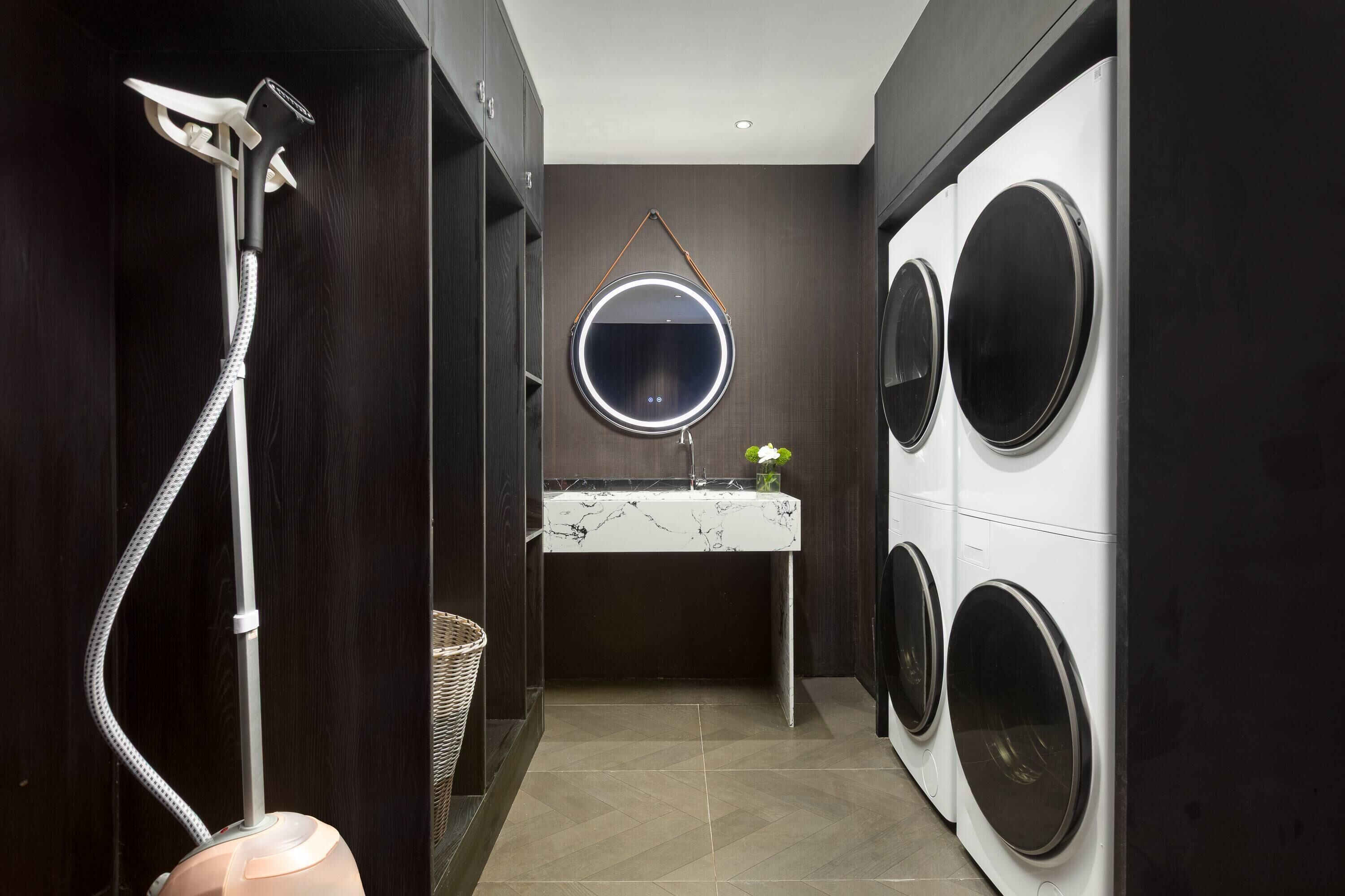 A compact laundry room with a washing machine, dryer, and a mirror above a sink.