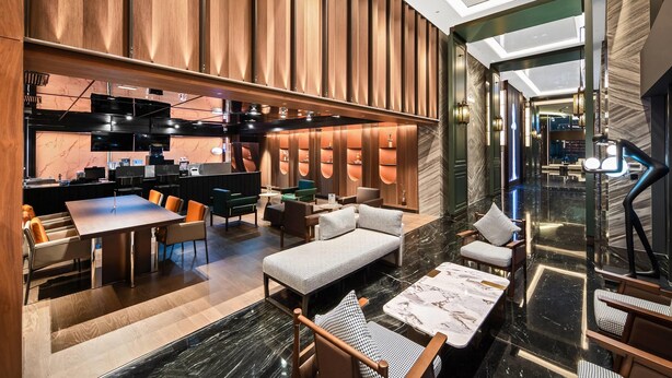 Um lobby de hotel moderno com área de refeições, assentos e balcão de recepção.