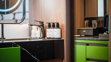 A modern kitchen with a marble countertop, a kettle, and a coffee machine.