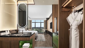 Casa de banho de hotel moderna com um espelho grande, uma toucador, uma pia e um roupão pendurado num suporte.