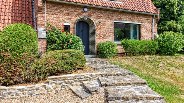 A brick house with a tiled roof, a stone pathway leading to the entrance, and well-maintained hedges. - Le Logis - Charmante Maison Proche Plage (Téteghem-Coudekerque-Village)