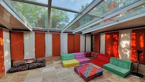 Ein sonnendurchflutetes Zimmer mit einer Glaskuppel, farbenfrohen Sofas und einem gefliesten Boden.