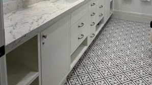 A bathroom with a marble sink, white cabinets, a large mirror, and patterned floor tiles. - Crowper Inn (Palo Alto)