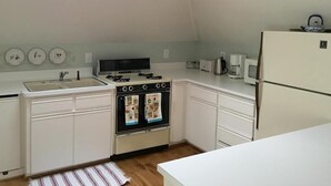 A compact kitchen with white cabinets, a double oven, a sink, and a refrigerator. - Crowper Inn (Palo Alto)