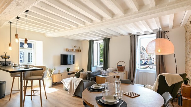 Een moderne woonkamer met een eethoek, houten vloeren en zichtbare balken.