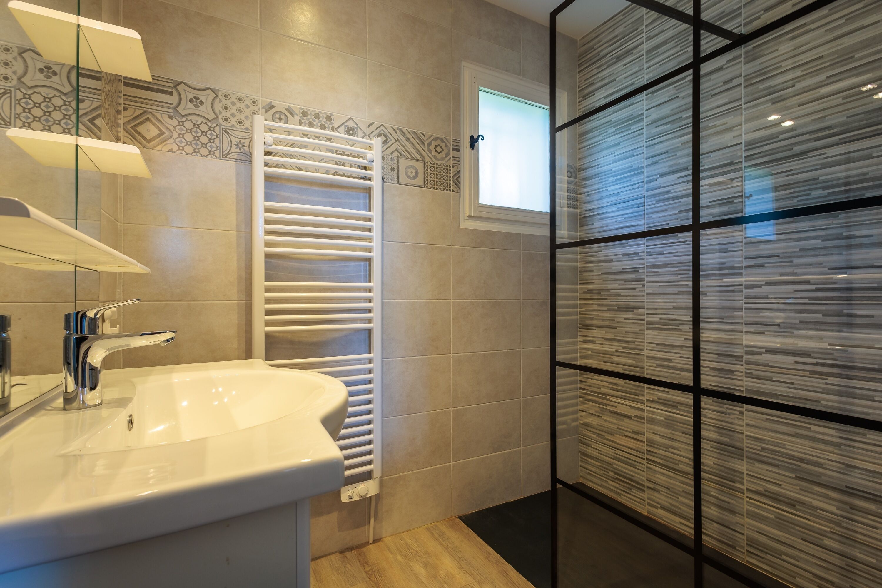 Ein modernes Badezimmer mit Waschbecken, Handtuchhalter und einer Duschkabine aus Glas.