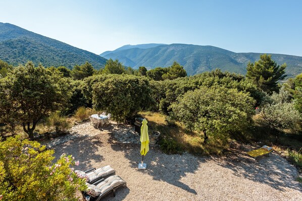 Un patio con mobiliario exterior, una sombrilla amarilla y vistas a las montañas.