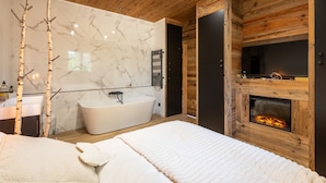 Un baño moderno con una bañera independiente, techo de madera y chimenea.