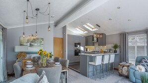 Una cocina moderna con una isla central, taburetes de bar y un comedor con una mesa dispuesta para cuatro.