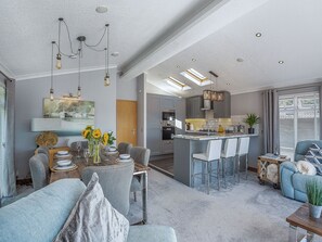 A modern kitchen with a central island, bar stools, and a dining area with a table set for four.