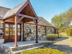 A stone building with a reception area, wooden doors, and a stone wall.
