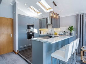 A modern kitchen with a central island, built-in appliances, and a skylight.