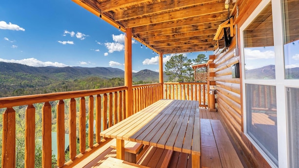 A wooden deck with a picnic table and a view of mountains.