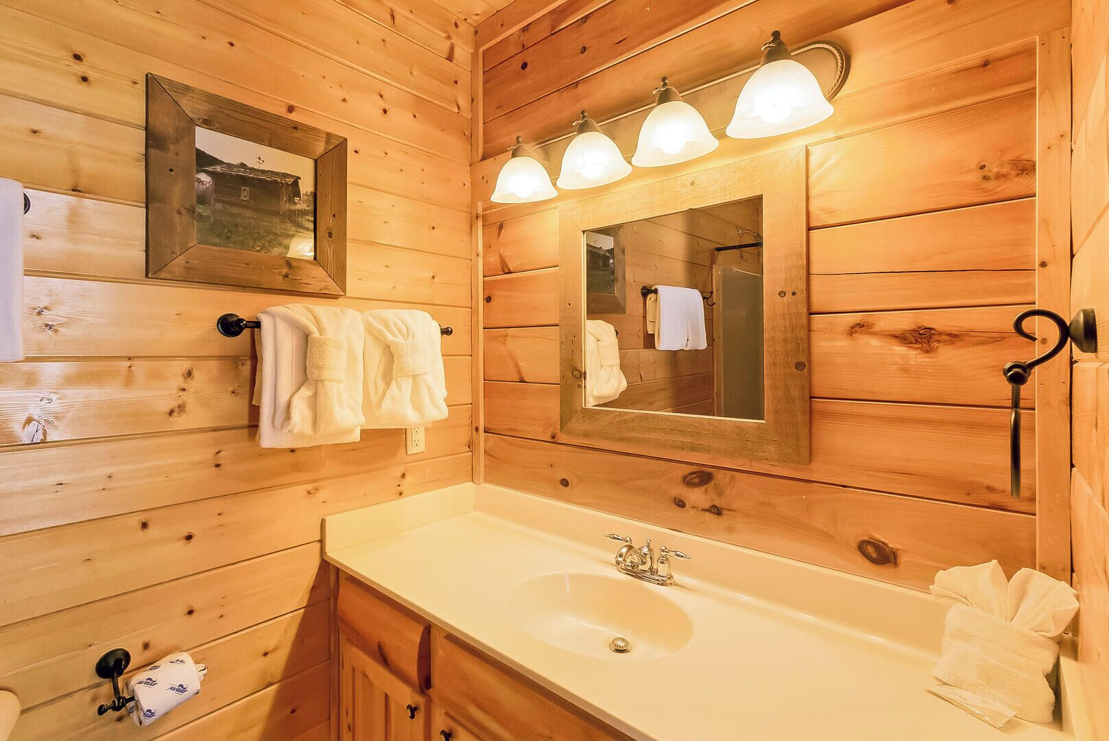 A wooden cabin-style bathroom with a sink, mirror, and towel rack.