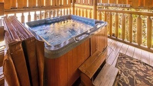 A wooden spa tub with a stone basin, wooden deck, and a wooden fence. - Center of Attention (Sevierville)