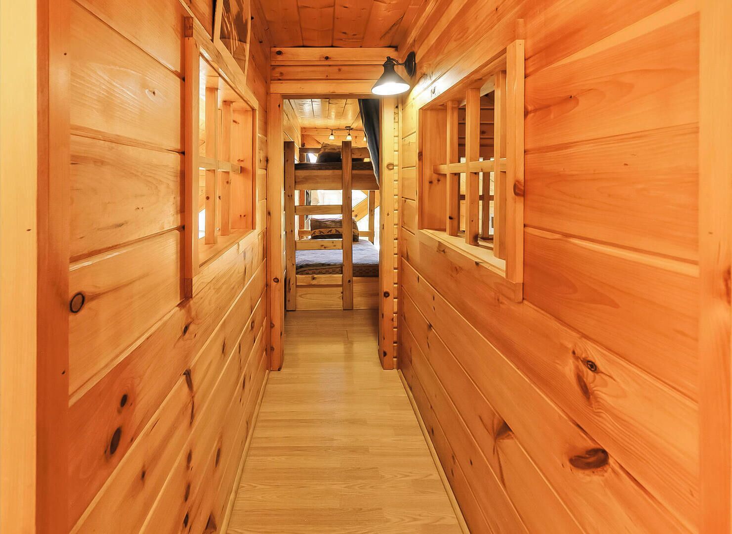 A wooden hallway with bunk beds and a ladder.