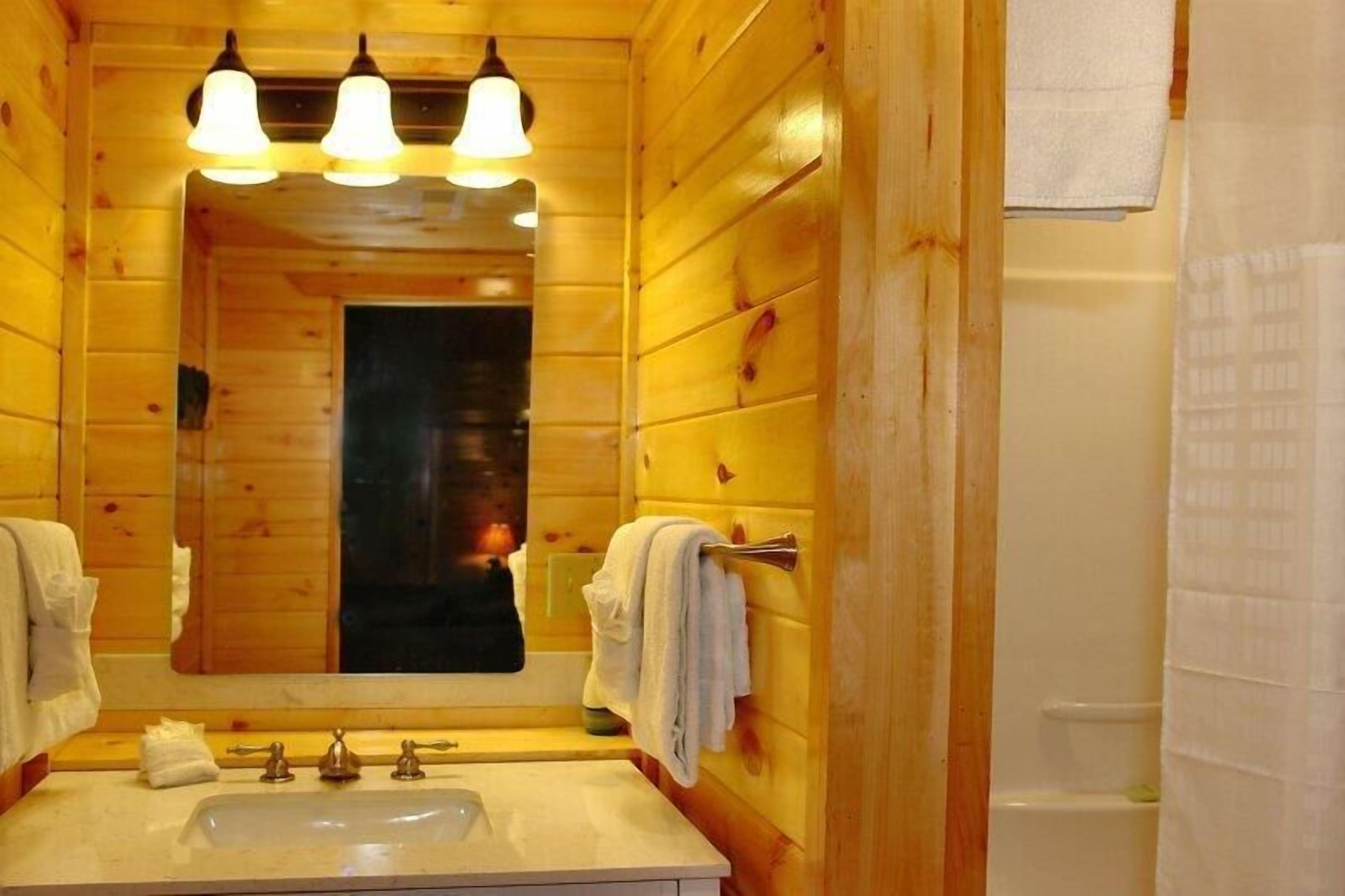 Un bagno in legno con uno specchio grande, due lavabi e una doccia.