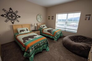 A bedroom with two beds, a large window, a bean bag chair, and a decorative wall piece. - Mountain View Condo 1501 (Pigeon Forge)