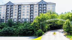 A multi-story residential building with balconies, a sign reading "MOUNTAINVIEW CONDOS," and a road leading to it. - Mountain View Condo 1501 (Pigeon Forge)