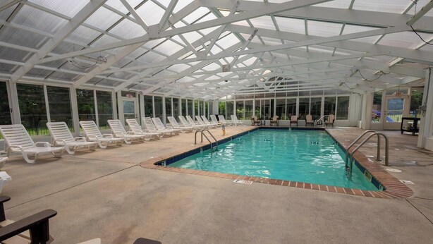 An indoor swimming pool with lounge chairs and a covered roof structure. - Mountain View Condo 1501 (Pigeon Forge)