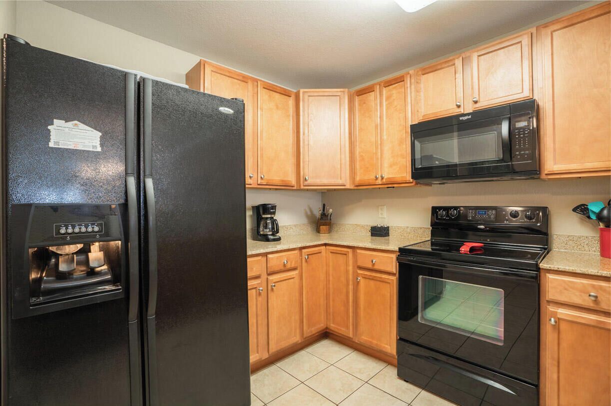 A kitchen with wooden cabinets, a black refrigerator, a microwave, and an oven.