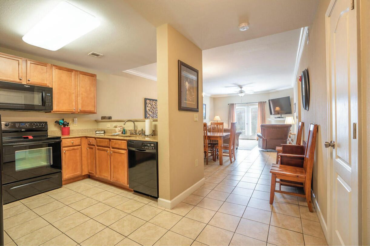 A kitchen with wooden cabinets, a microwave, an oven, and a dishwasher. There is a dining area with a table and chairs.