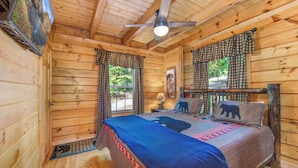 A cozy cabin bedroom with a bed, curtains, a ceiling fan, and a window. - Beary Nice to Meet You! (Sevierville)