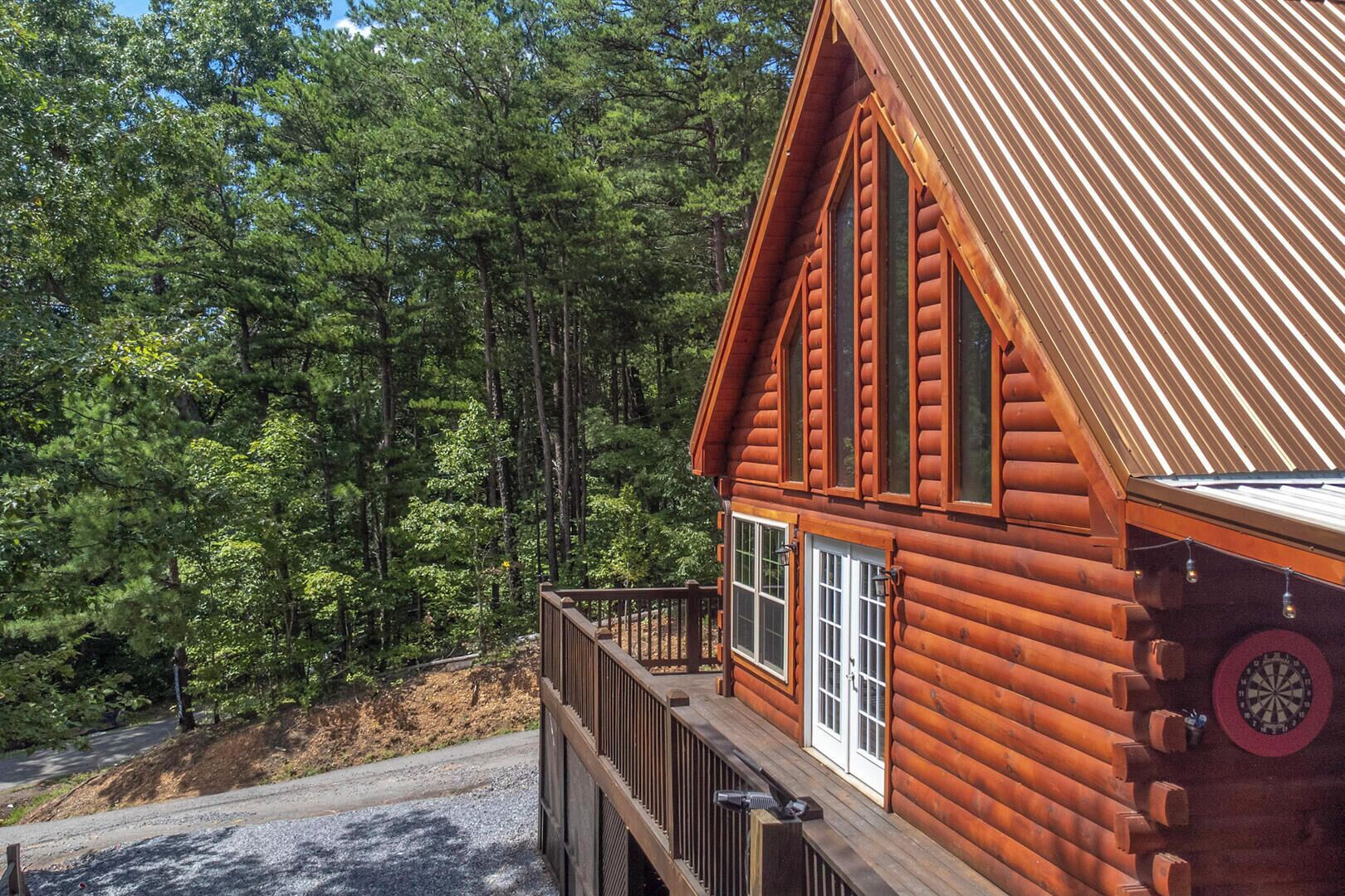 Une cabane en rondins dotée d’un balcon, entourée d’une forêt dense.
