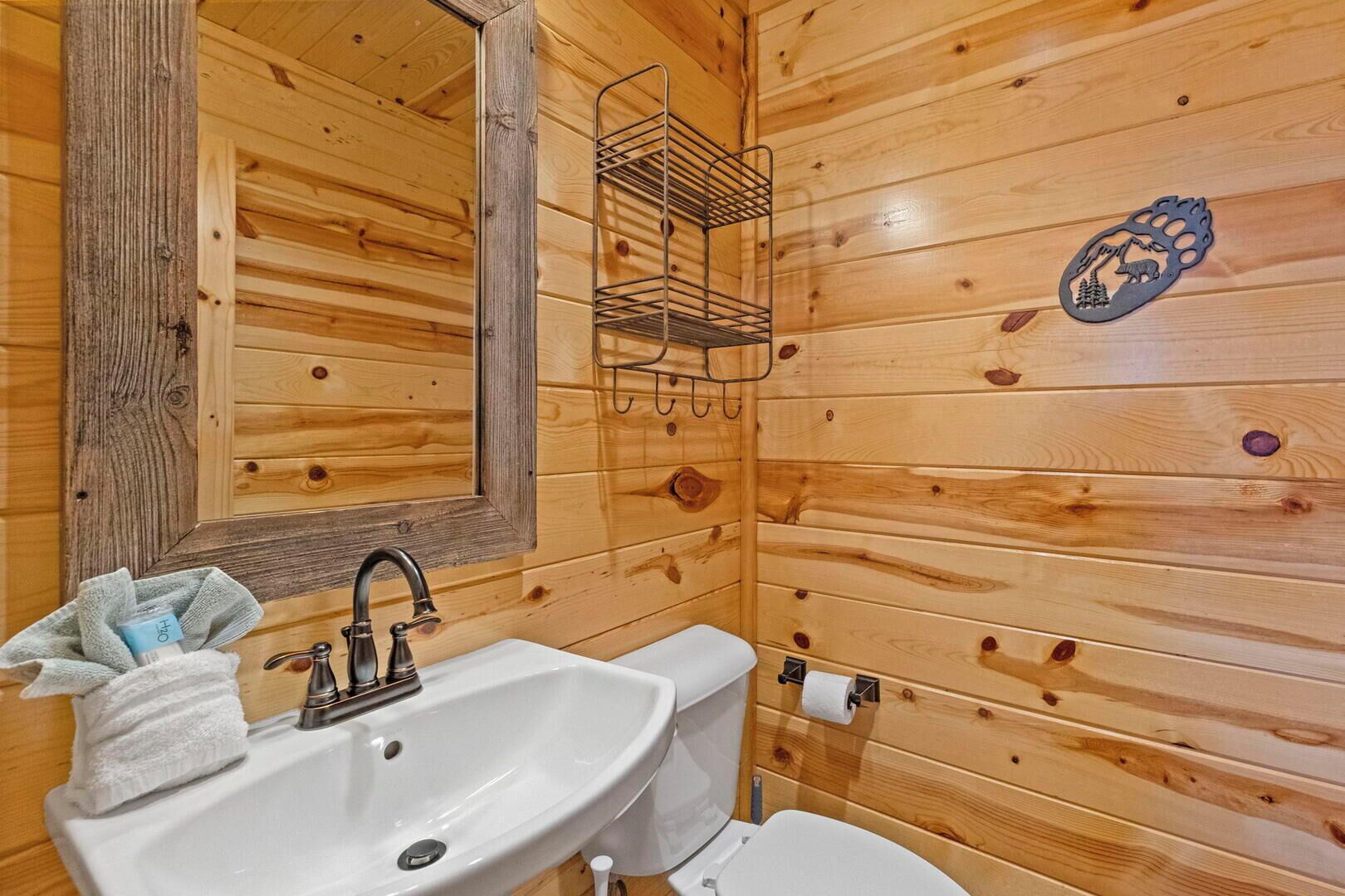 Un baño de cabaña de madera con lavamanos, inodoro y espejo.