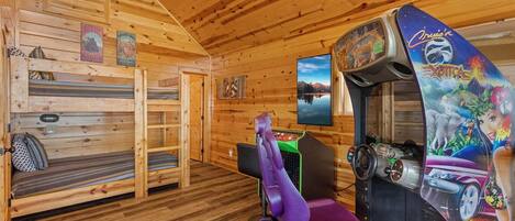 A cabin with wooden walls and floors, a bunk bed, a Nintendo gaming console, and a painting of a landscape.