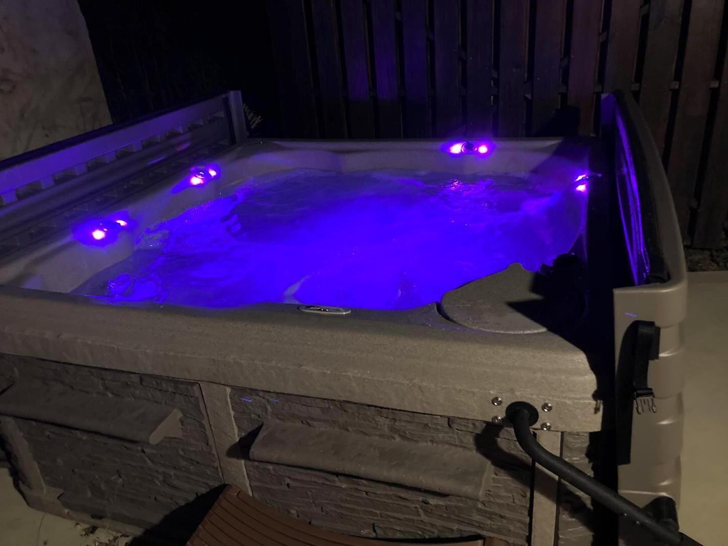 A hot tub with a stone exterior and a wooden deck in front.