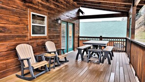 A wooden deck with Adirondack chairs and a picnic table.