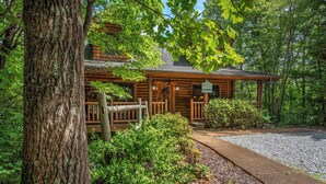 A rustic log cabin with a porch, surrounded by dense forest. - Leconte Lookout (Sevierville)