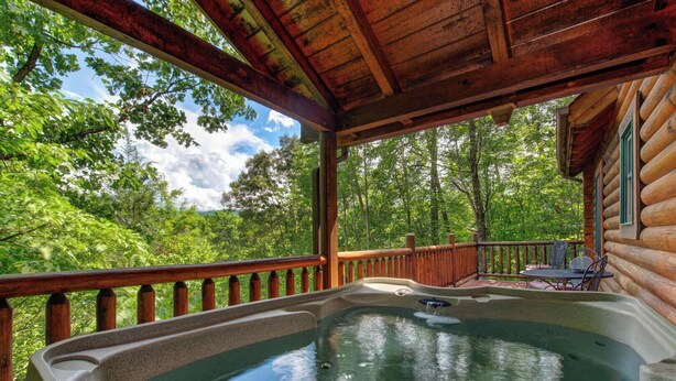 A hot tub on a wooden deck with a view of a forest. - Leconte Lookout (Sevierville)