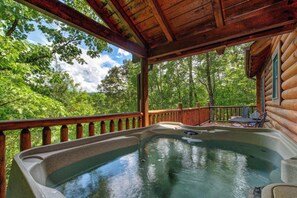 A hot tub on a wooden deck with a view of a forest. - Leconte Lookout (Sevierville)
