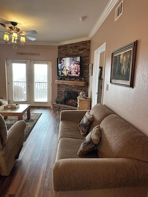 A living room with a stone fireplace, a television, and a couch. - Mountain View Condo 3702 (Pigeon Forge)