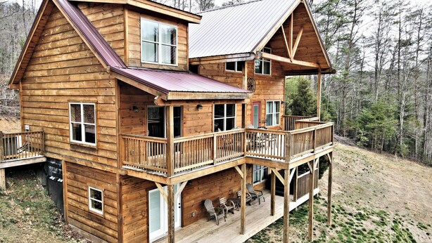 A wooden cabin with a balcony, multiple windows, and a porch area with seating. - Wagon Wheel (Sevierville)