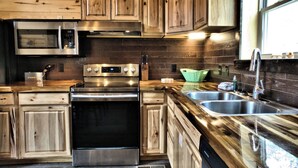 A modern kitchen with wooden cabinets, stainless steel appliances, and a large window. - Wagon Wheel (Sevierville)