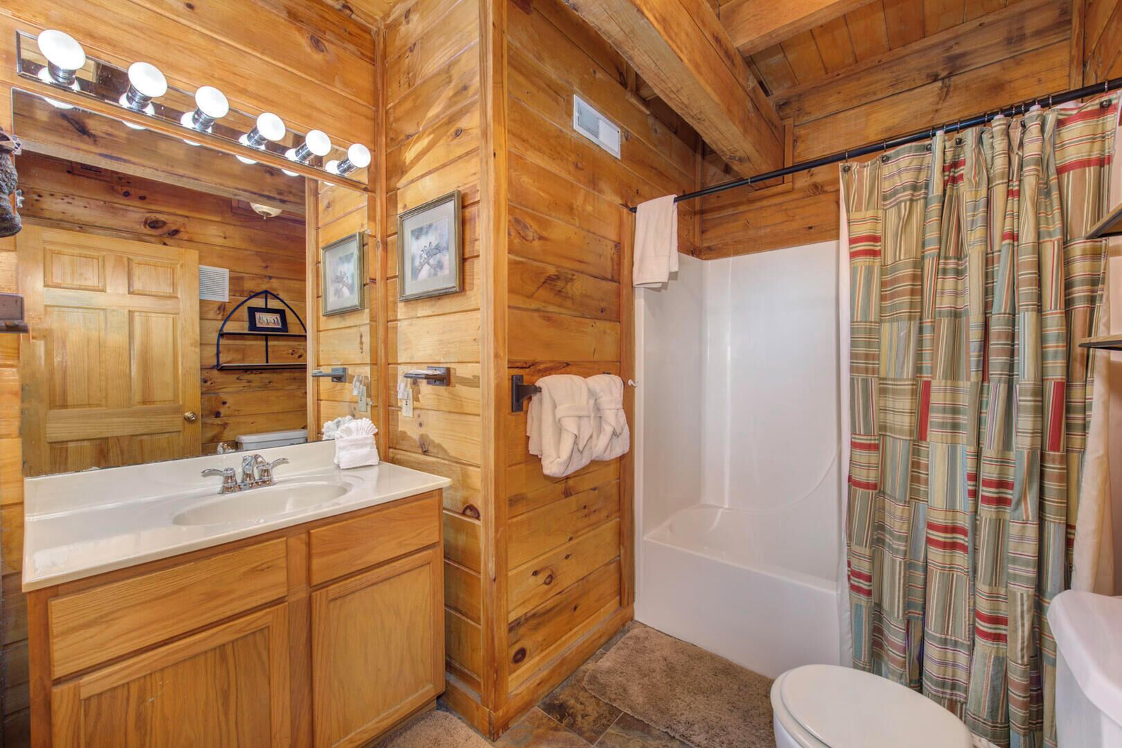 A wooden bathroom with a sink, mirror, and a shower curtain.